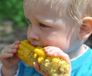 niño comiendo mazorca de maiz