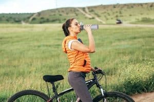 mujer en bicicleta bebiendo agua