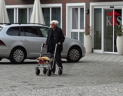 anciana caminando en la calle con su andador de ruedas