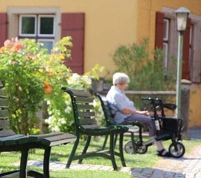 anciana sentada en un banco con su andador