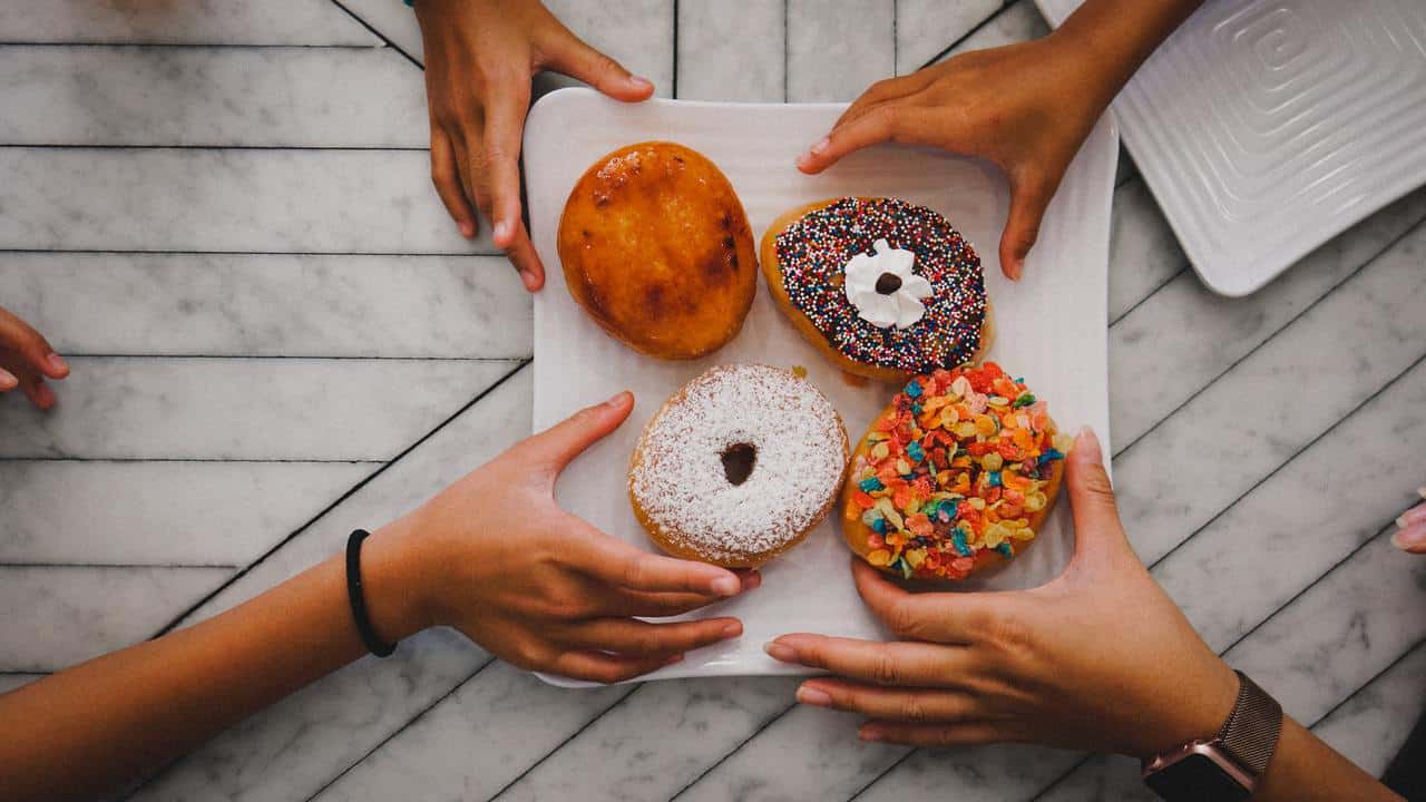 4 personas tomando donuts de un plato