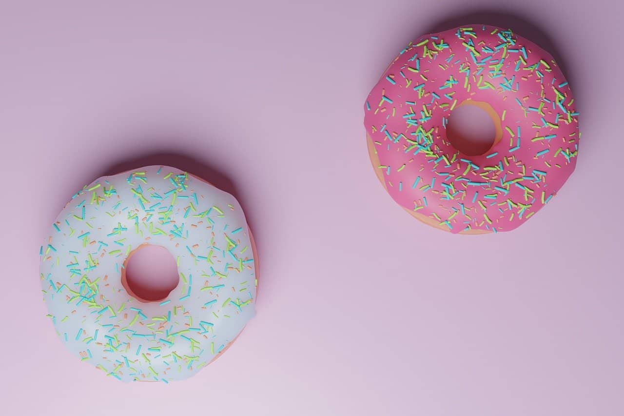 2 donuts de colores sobre un fondo rosa