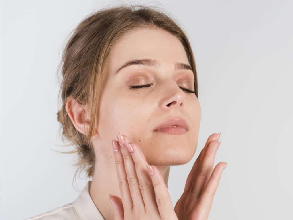 Mujer joven masajeándose la cara.
