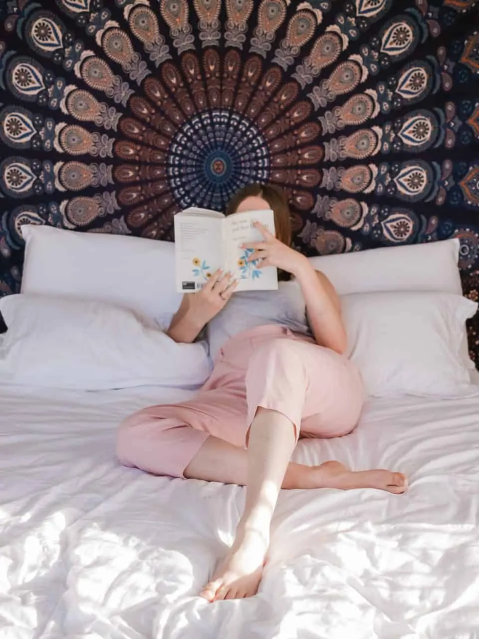 Mujer leyendo un libro a recostada de las almohadas