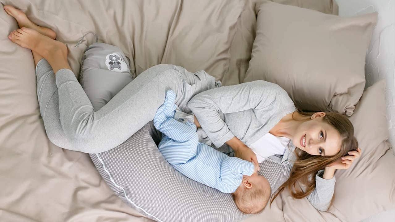 Mujer amamantando a un bebé usando una almohada