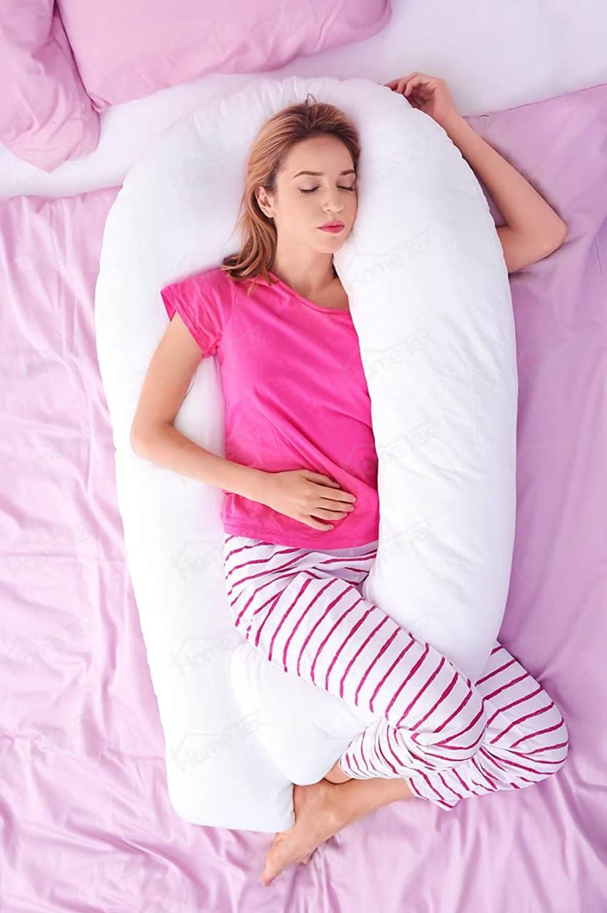 Mujer embarazada acostada usando una almohada tubular