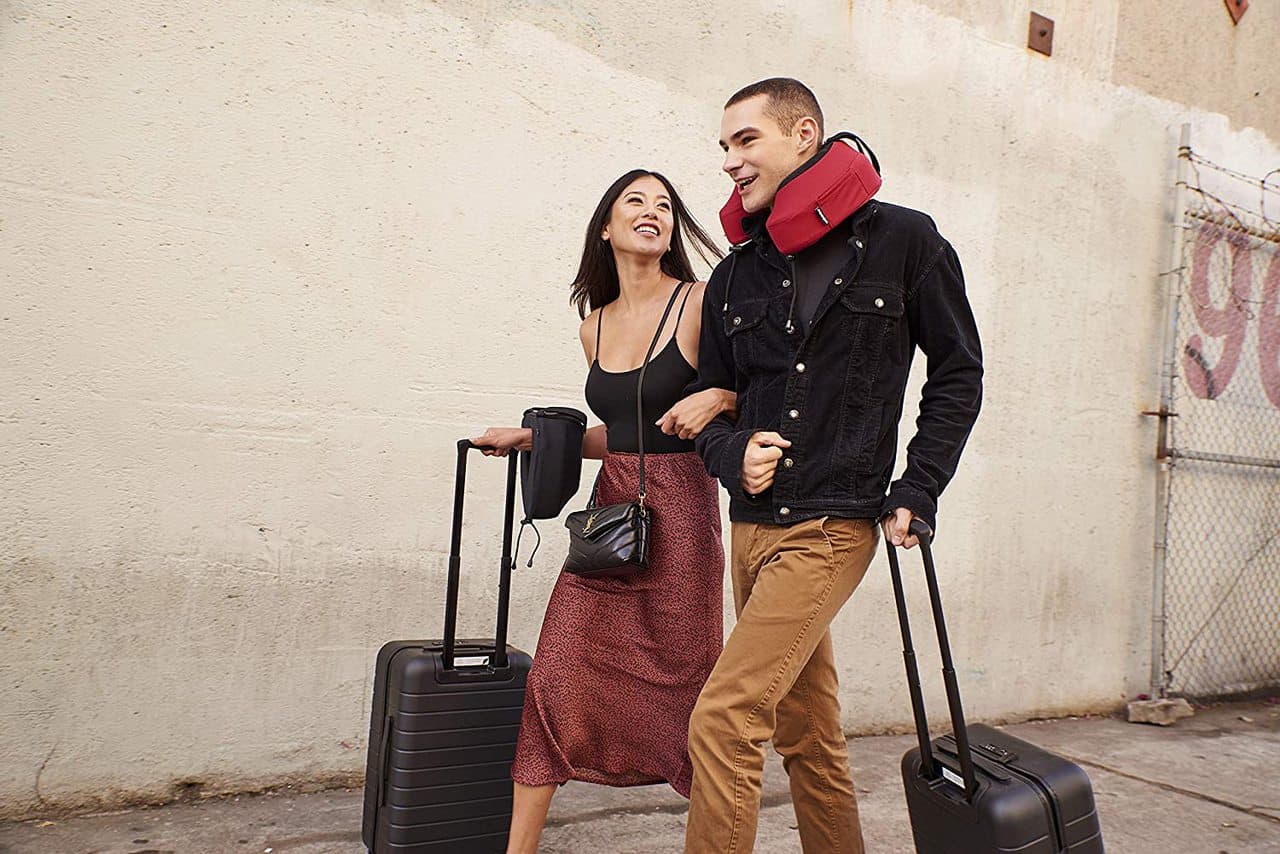 Dos personas con maletas y almohadas para viajar